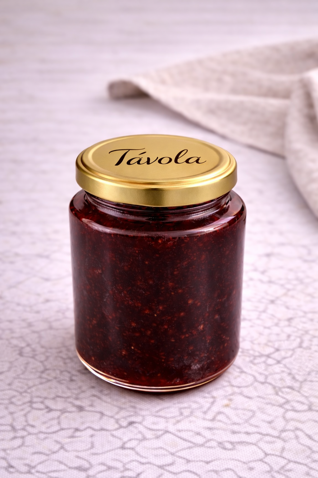 Pote de geleia de amora com morango da Tavola sobre uma bancada clara.